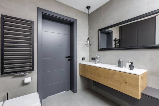 Дверь в ванную комнату серого цвета с отделкой плиткой светло-серого цвета.