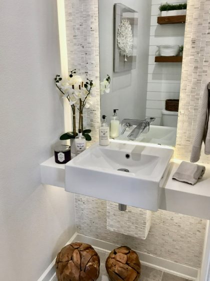Раковина в ванной комнате с каменным фоном и зеркалом с подсветкой