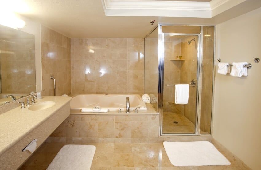 Ванная комната со стеклянной душевой кабиной, настенными вешалками для полотенец и травертиновым полом