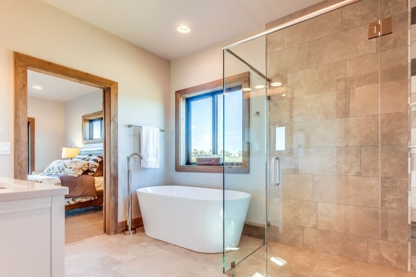 En suite bathroom with glass enclosed shower, freestanding tub, and travertine tile floor