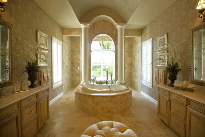 Роскошная ванная комната с гидромассажной ванной у арочного окна, колонн и травертинового пола