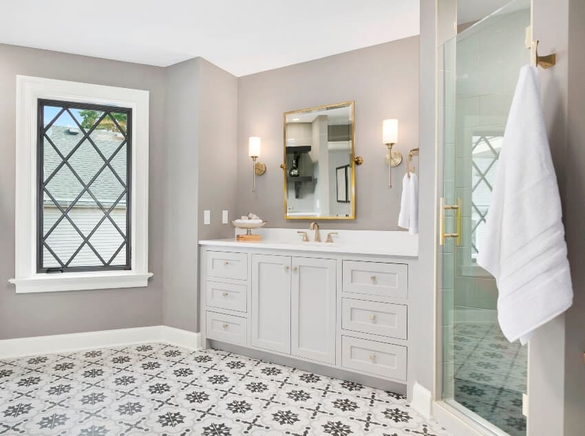 Великолепный интерьер ванной комнаты с красивой узорчатой ​​напольной плиткой, белой стойкой с раковиной и душевыми дверями из матового стекла
