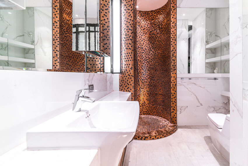 Ванная комната с круглым ограждением, душевой стеной из мозаичной плитки, раковиной и зеркалом.