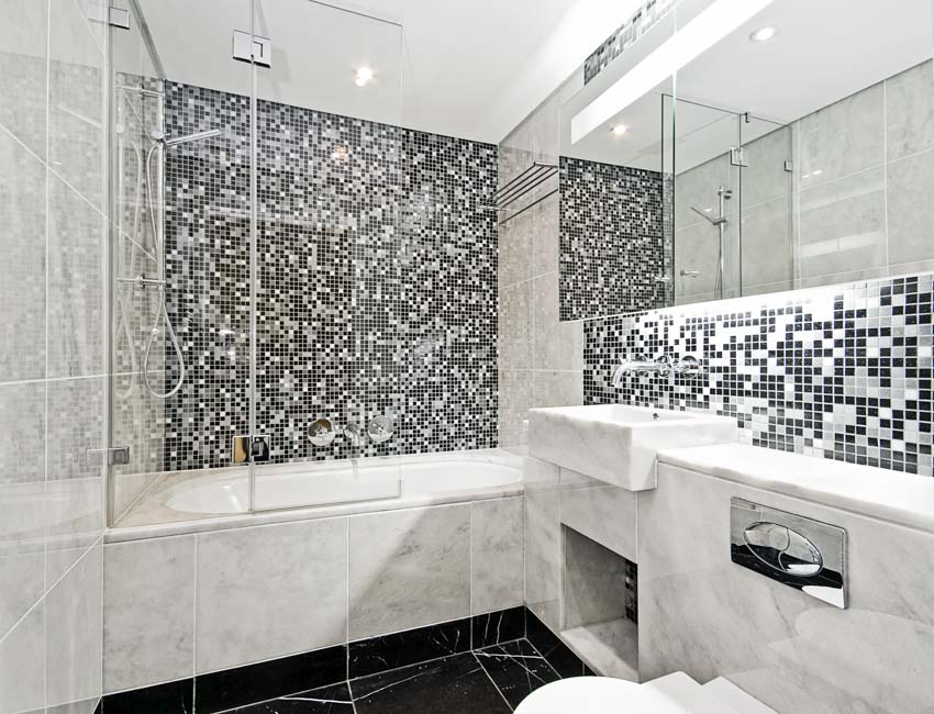 Ванная комната с ванной, кафельным полом, косметическим зеркалом, мозаичной плиткой на стене душа и столешницей.