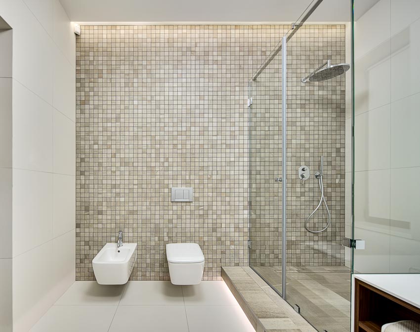 Ванная комната с мозаичной душевой стеной, стеклянной дверью, туалетом и биде