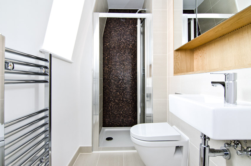 Ванная комната с держателем для полотенец, душевой стеной из мозаичной плитки, туалетом, зеркалом, раковиной и смесителем.