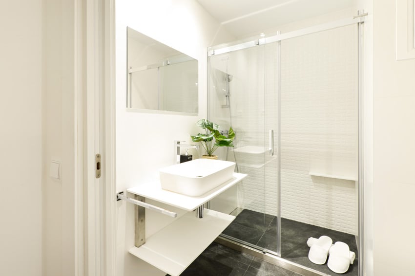 Ванная комната с раздвижной панельной дверью, плавающей столешницей, раковиной, зеркалом и кафельным полом.