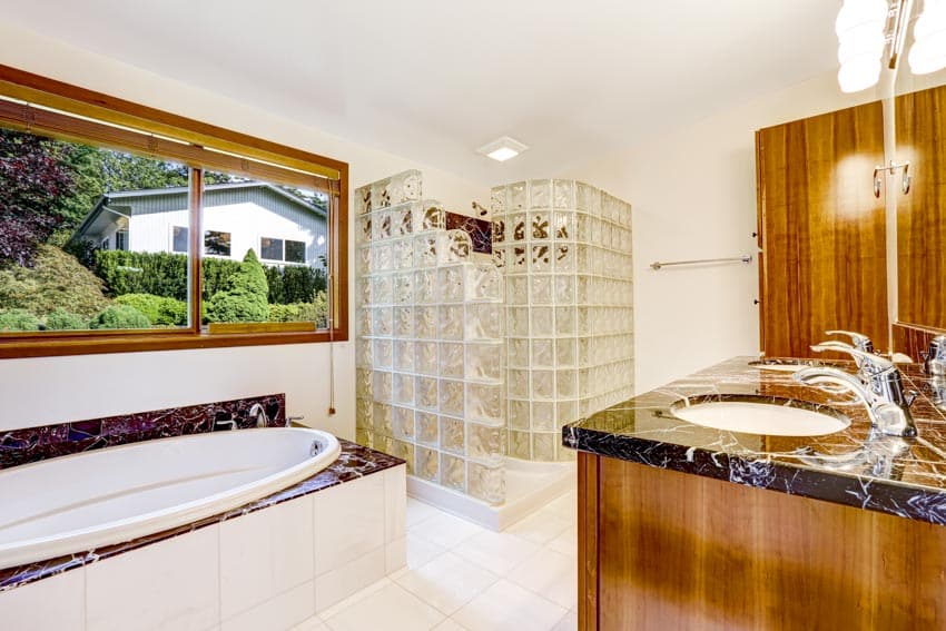 Ванная комната с душевой кабиной из стеклоблоков, ванной, столешницей, раковиной и окном