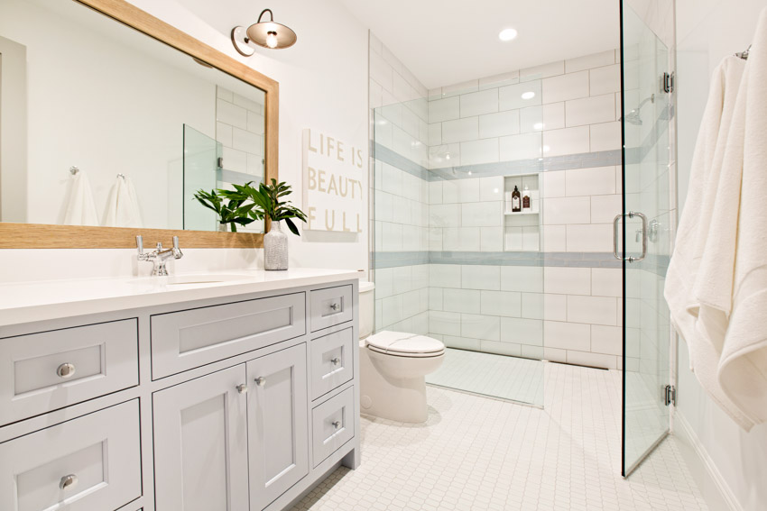 Ванная комната с белой стеклянной душевой стеной, стеклянной дверью, косметическим зеркалом, туалетом и ящиками