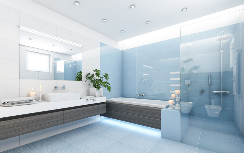 Современная ванная комната с душем из стеклянной плитки, ванной, плавающим туалетным столиком, зеркалом, столешницей и раковиной.