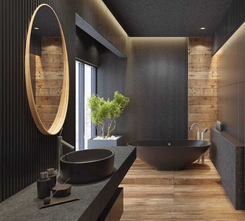 Роскошная современная ванная комната с черной гранитной столешницей, отделанной кожей, на фоне полуглянцевых стен, черной ванной и деревянными полами.