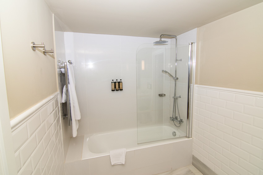 Ванная комната с душевой стенкой из стекловолокна, стеклянной перегородкой, ванной и держателем для полотенец.