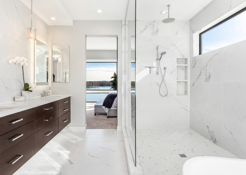Ванная комната с фарфоровой душевой стенкой, стеклянной перегородкой, ящиками, столешницей, зеркалом и окном. 