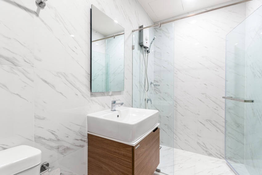 Ванная комната с кварцевыми душевыми стенками, зеркалом, раковиной и стеклянным ограждением