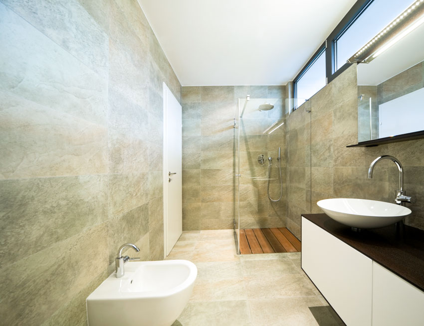 Ванная комната с гранитными душевыми стенами, туалетом, раковиной, столешницей, зеркалом и окном.