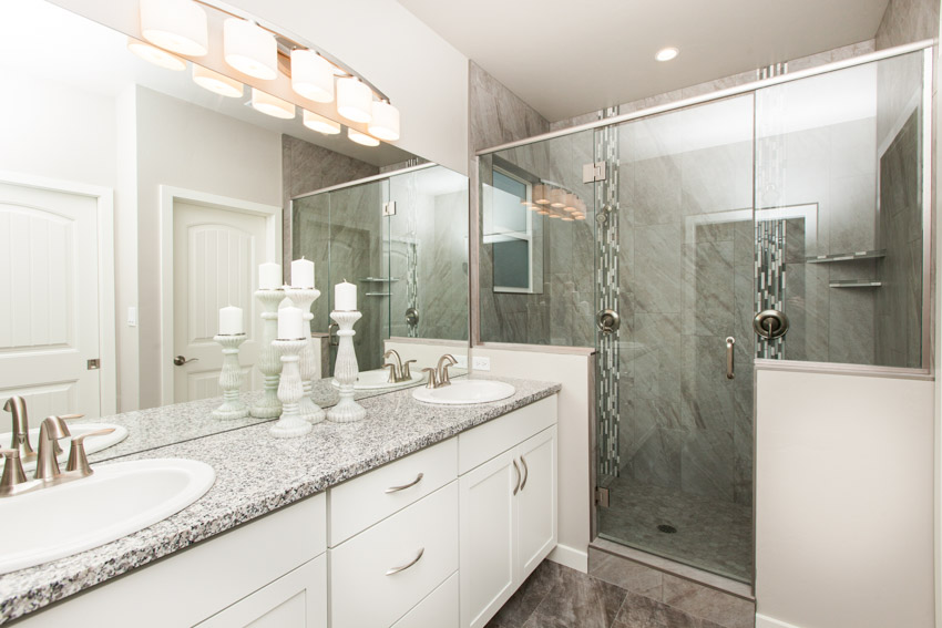 Ванная комната со стеклянной стеной для душа с твердой поверхностью, дверью, столешницей, ящиками, раковиной и зеркалом