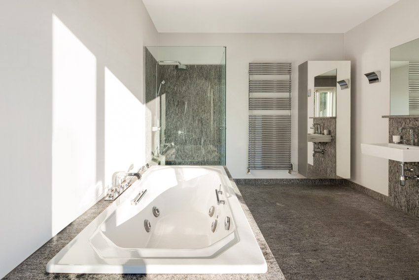 Ванная комната с гранитными душевыми стеновыми панелями, ванной, стеклянной дверью, туалетным столиком, зеркалом и плавающей раковиной.