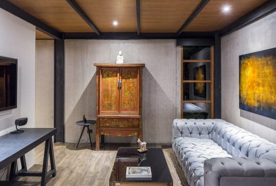 Дизайн простой гостиной с бетонными стенами и деревянным потолком
