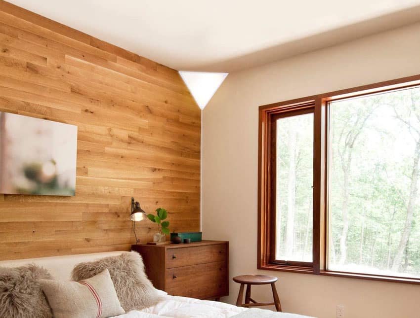 Спальня с угловым настенным бра, деревянной акцентной стеной, табуретом, комодом и окном