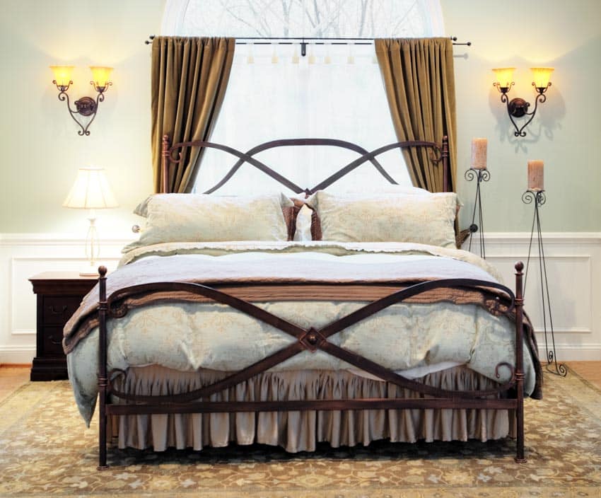 Переходная спальня с настенными бра, матрасом, постельным бельем, подушками, ковром, тумбочкой, лампой и занавесками на окнах