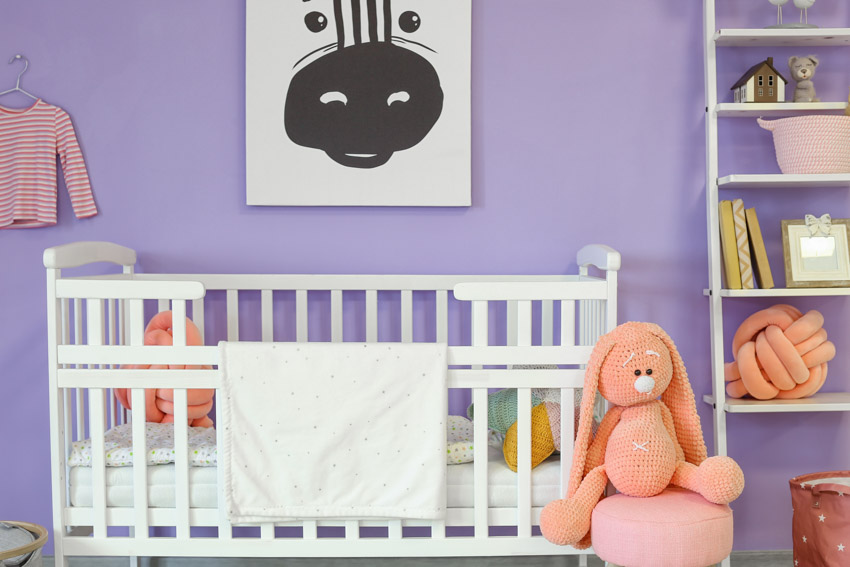 Детская комната с кроваткой, полками и окрашенной в лавандовый цвет стеной