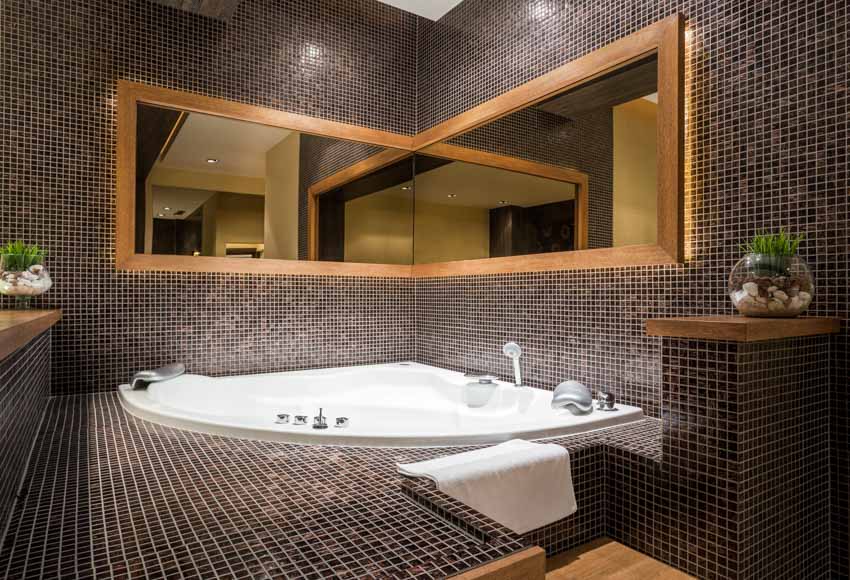 Ванная комната с ванной, черной мозаичной плиткой, зеркалом и комнатными растениями