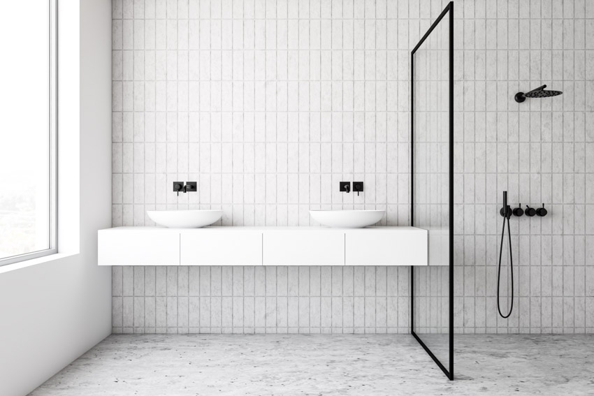 Минималистская ванная комната с белой плиткой kit kat на стене, плавающим туалетным столиком, раковиной, смесителем, перегородкой и душевой зоной