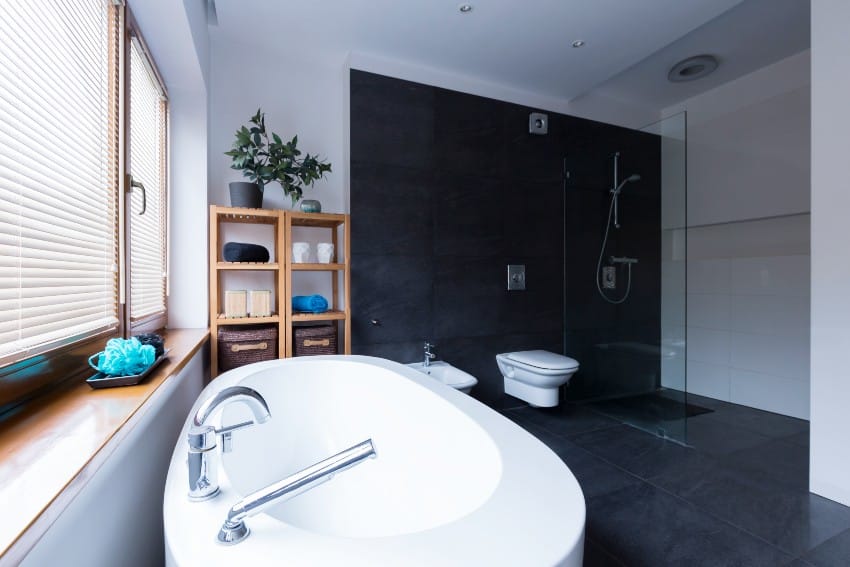 Современная и просторная ванная комната с черной акцентной стеной, черной плиткой и прозрачной душевой кабиной
