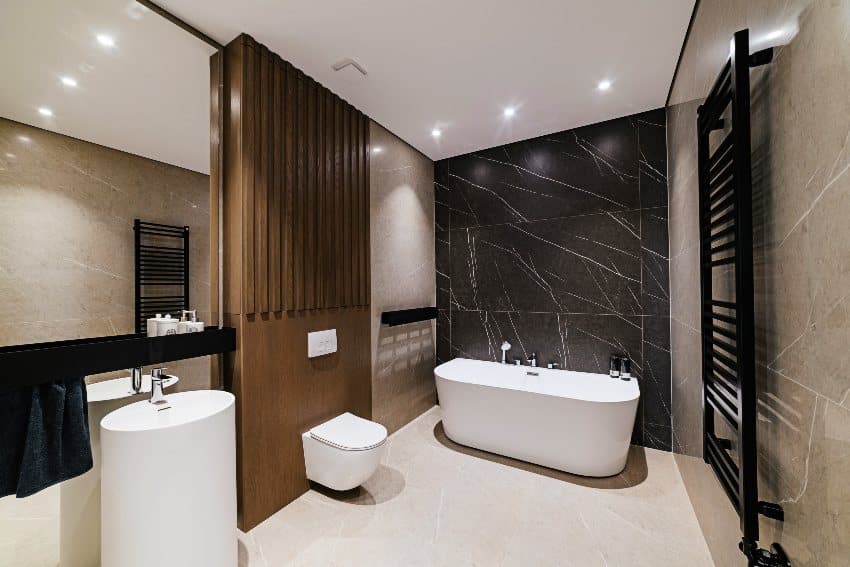 Современный дизайн ванной комнаты с большой каменной ванной, акцентной стеной из черного мрамора и кафельным полом.