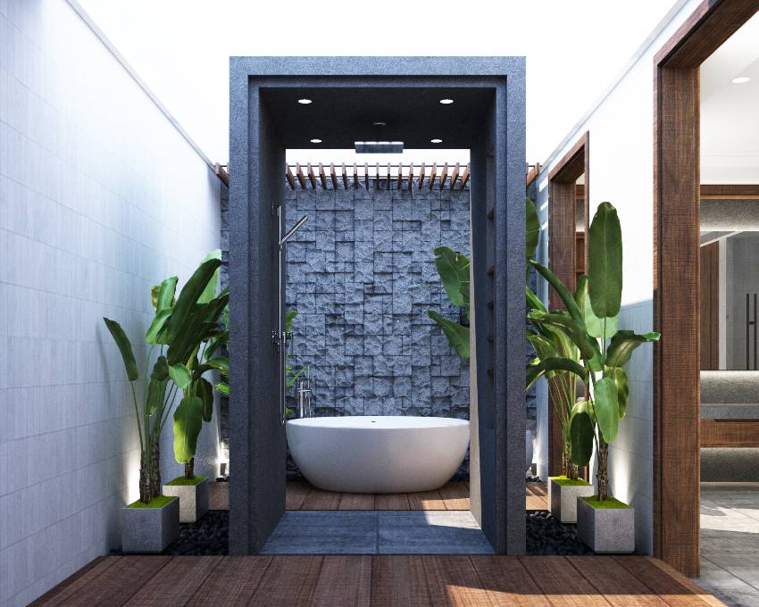 Современная ванная комната с каменной акцентной настенной плиткой, деревянным полом и растениями сбоку.