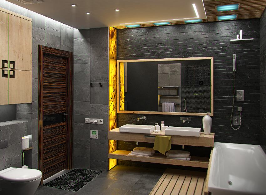 Черный современный интерьер ванной комнаты с акцентом желтого света на боковой стене, ванне, деревянной столешнице и туалете