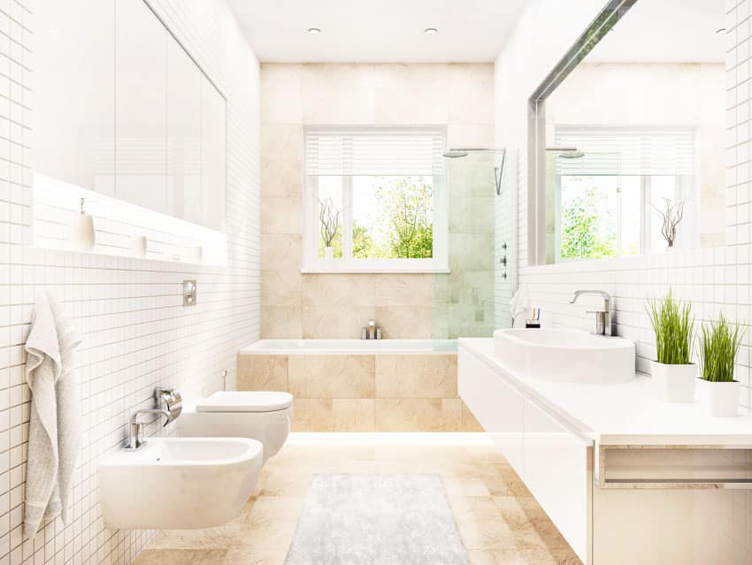 Ванная комната с плиткой от пола до потолка, туалетом, биде, ванной, зеркалом, столешницей, плавающей раковиной и зеркалом.