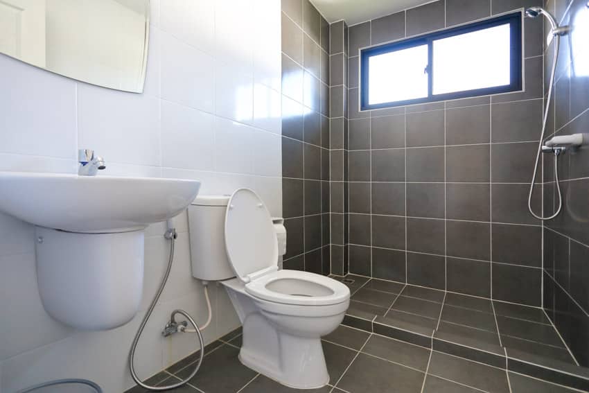 Ванная комната с черной плиткой от пола до потолка, туалетом, раковиной, биде, душем и зеркалом