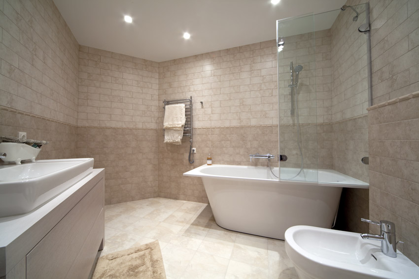 Ванная комната с известняковой плиткой от пола до потолка, ванной, раковиной и биде