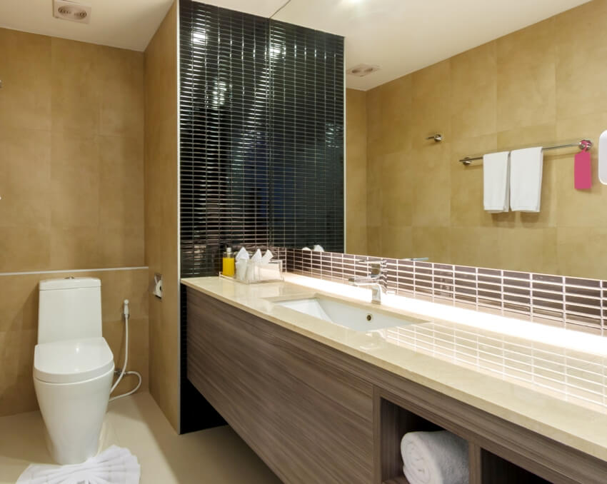 Простой интерьер ванной комнаты с столешницей из ламината, облицованной плиткой, и туалетом