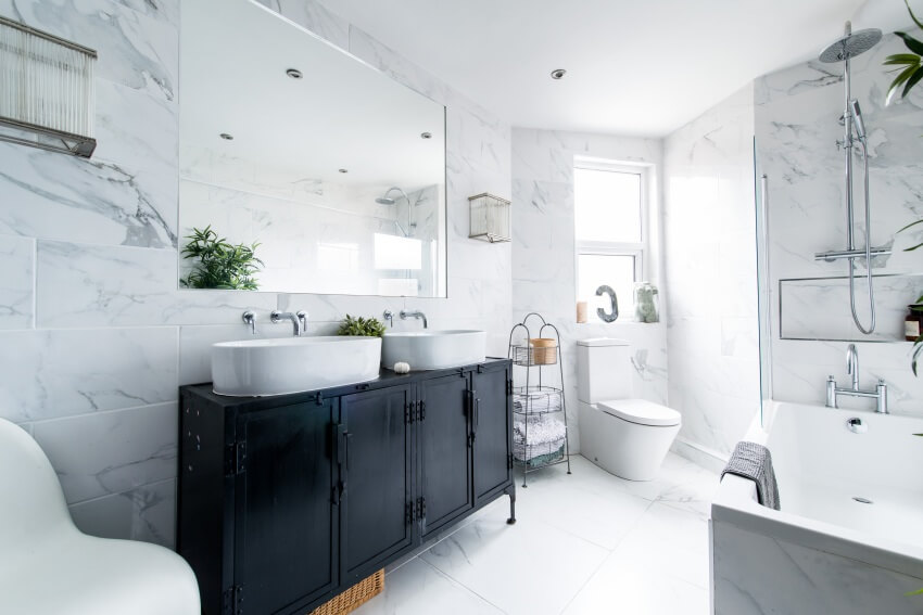 Чистая яркая стильная дизайнерская современная ванная комната с черной столешницей, ванной и другой сантехникой