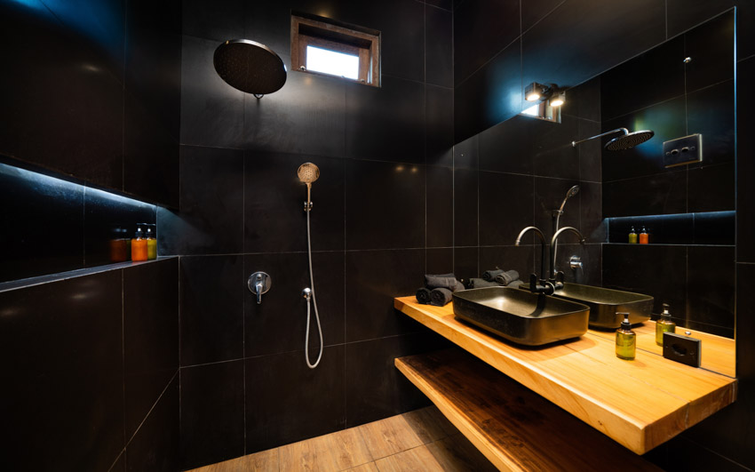 Черная ванная комната с плавающей древесиной, столешницей, крупноформатной плиткой, душевой стенкой, окном, раковиной, смесителем и зеркалом