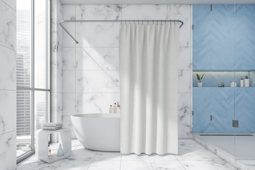 Ванная комната с удлиненной занавеской для душа, мраморной стеной, ванной, табуретом и окнами.