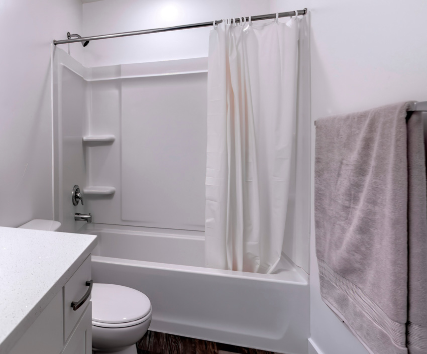 Ванная комната с карнизом для душевой занавески, ванной, унитазом и держателем для полотенец.