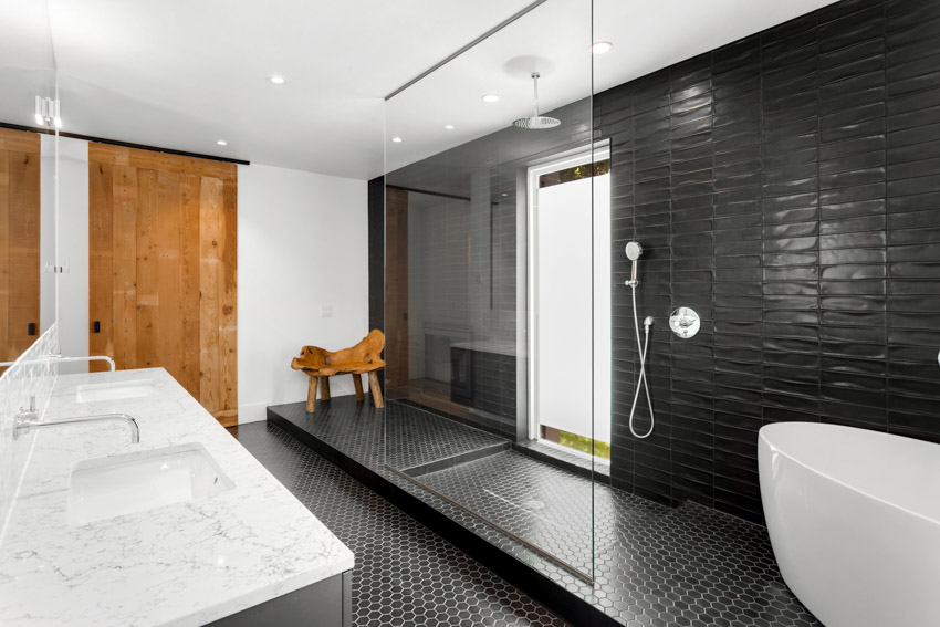 Ванная комната с черной акцентной стеной, душевой кабиной, ванной, стеклянной перегородкой, белой столешницей и раковиной. 