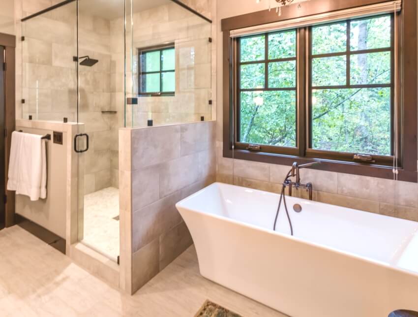 Традиционная ванная комната с мраморной плиткой, ванной, душем с половинной стенкой и стеклянными дверями