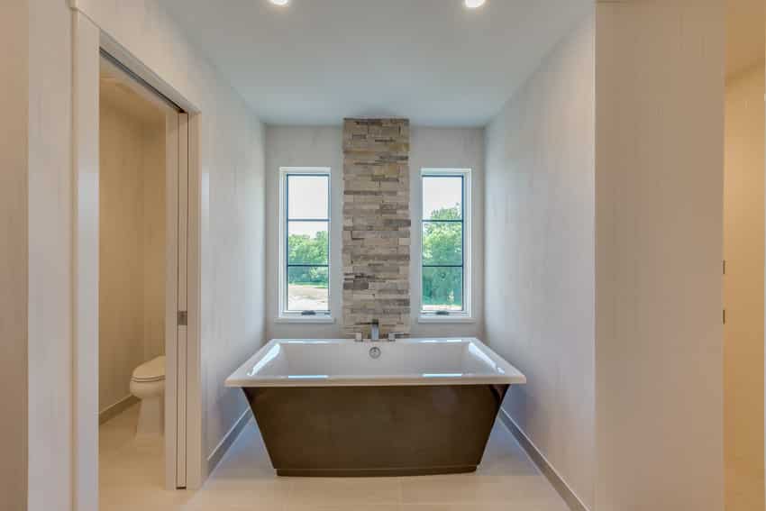Ванная комната с известняковым полом, стенами, ванной и окнами