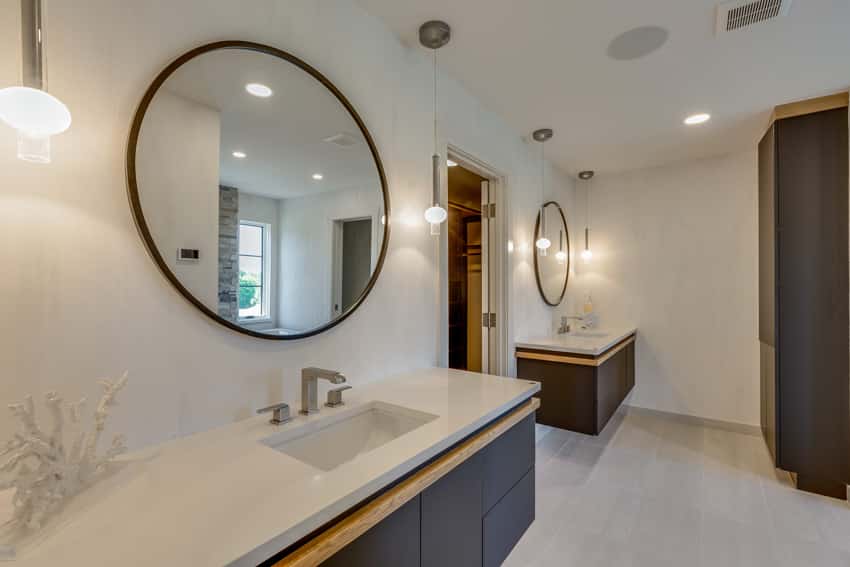 Туалетный столик в ванной комнате с известняковым полом, зеркалом, столешницей, раковиной, подвесным туалетным столиком и настенными светильниками.