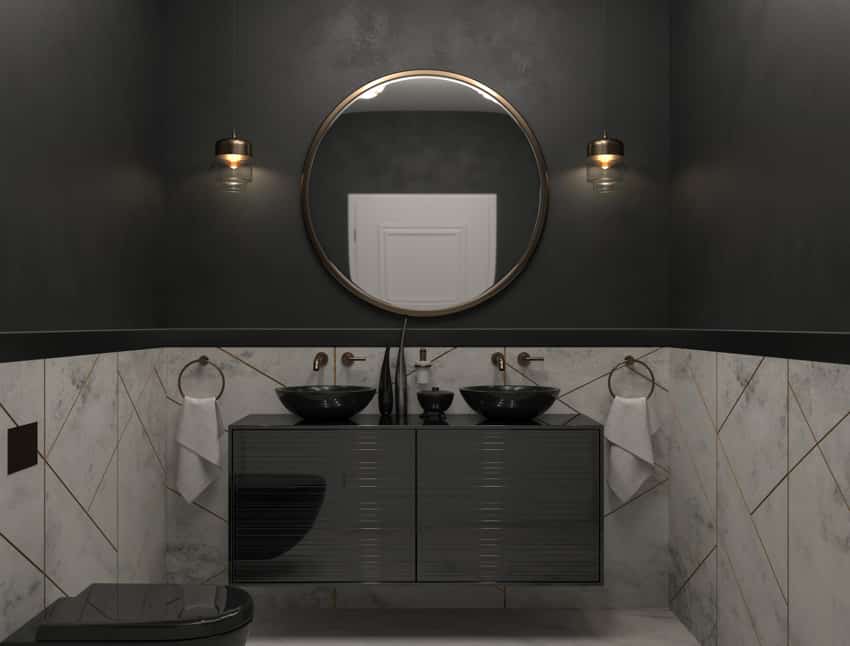 Ванная комната с черной столешницей, двумя раковинами, зеркалом, настенными светильниками и туалетом.