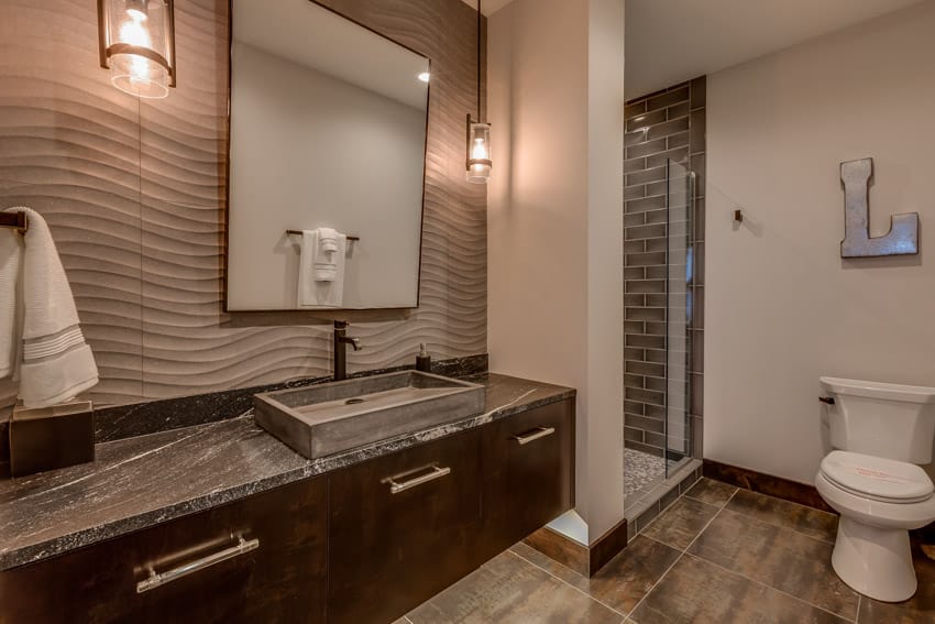 Ванная комната с деревянным полом, черной столешницей, раковиной, смесителем, зеркалом, акцентной стеной и унитазом.