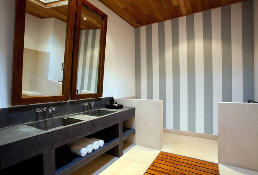 Ванная комната с полосатой акцентной стеной, черной столешницей, раковинами, смесителями и зеркалами