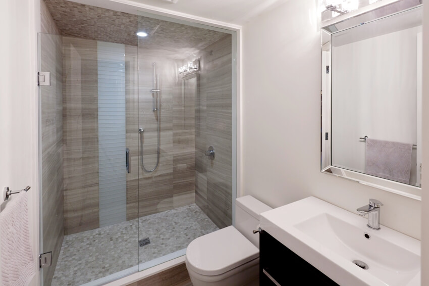 Современная ванная комната с обнаженными стенами и душевой кабиной на полу из пенни-плитки