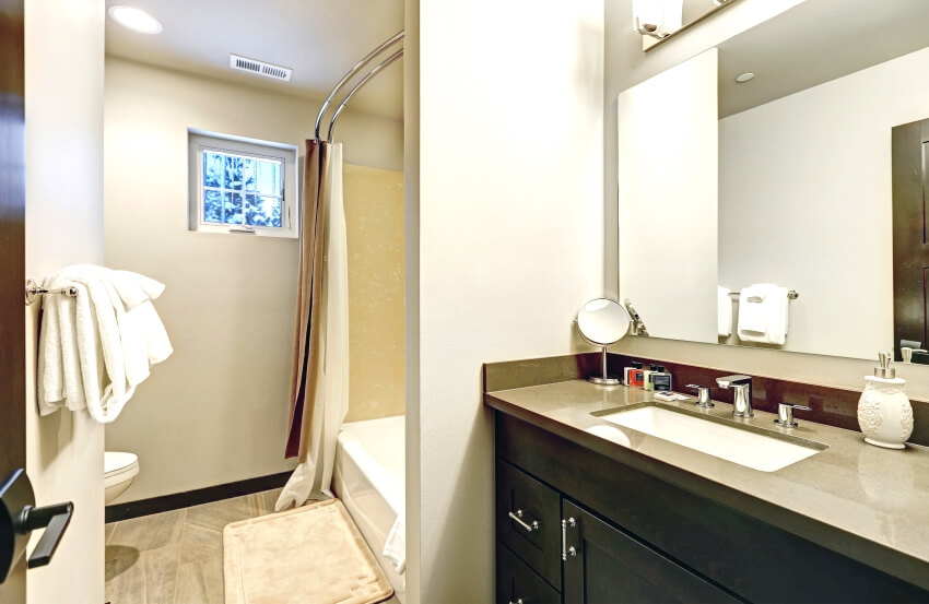 Светло-бежевая ванная комната с туалетным столиком и душем с изогнутой двойной штангой для занавески для душа