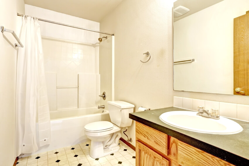 Ванная комната с линолеумным полом, деревянным шкафом с зеркалом и белой ванной с занавесками.
