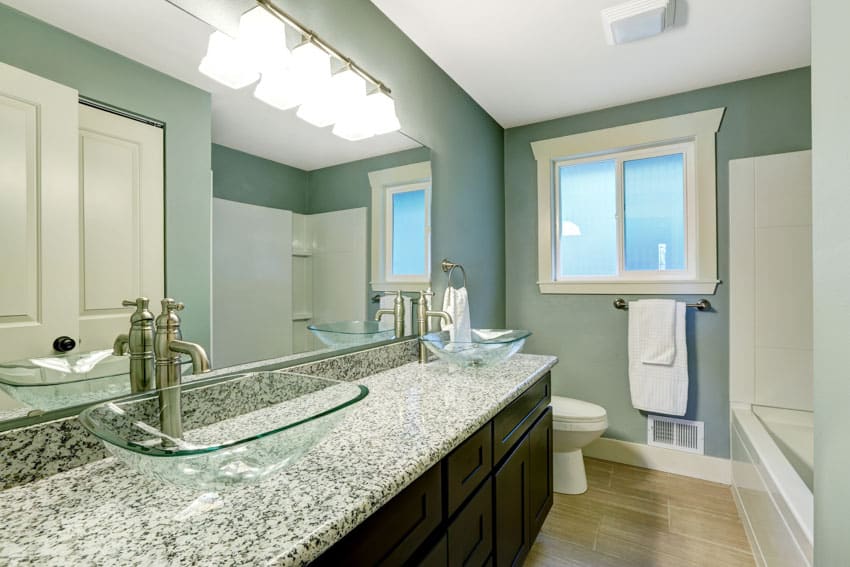 Ванная комната с зеленой стеной, гранитной столешницей, зеркалом, деревянным полом, туалетом и окном